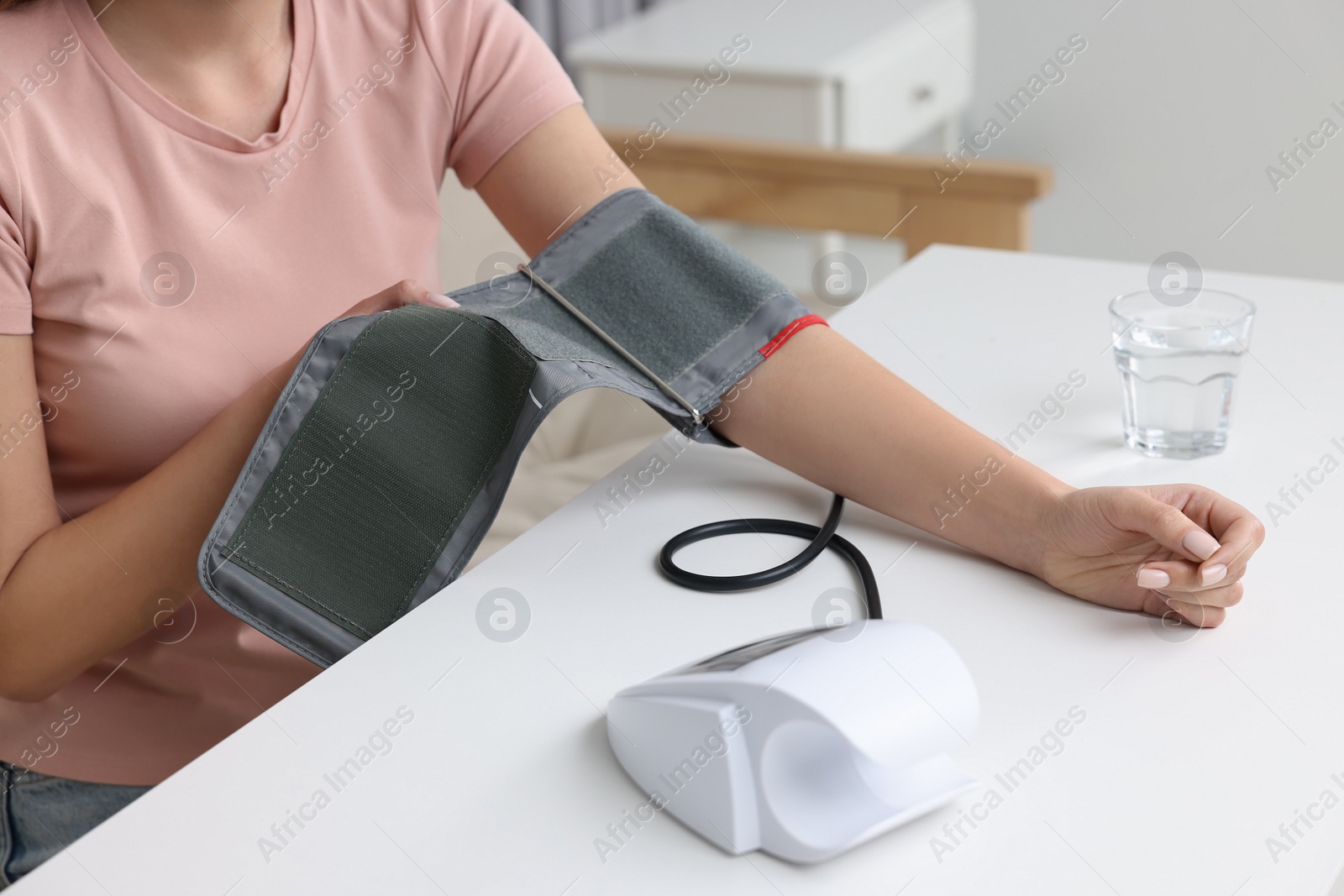 Photo of Woman measuring blood pressure with tonometer indoors, closeup