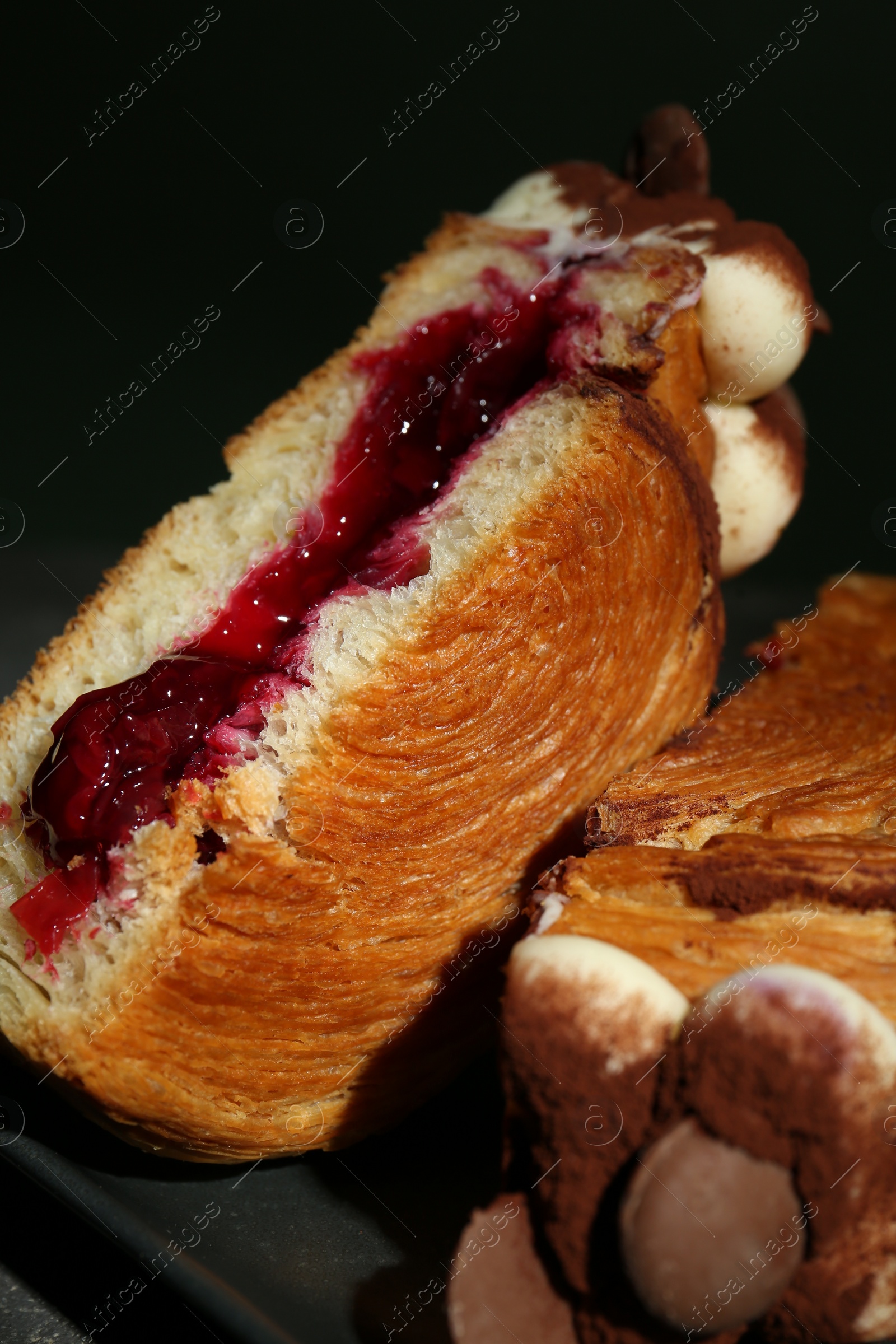Photo of Round croissant with jam, cream and chocolate chips on table, closeup. Tasty puff pastry