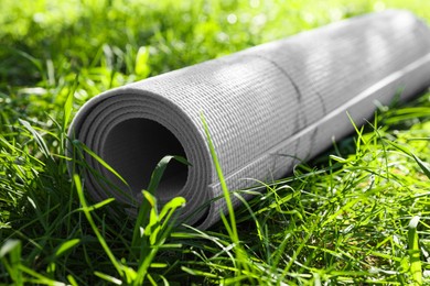 Rolled karemat or fitness mat on green grass outdoors, closeup