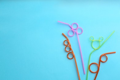 Photo of Colorful plastic drinking straws on light blue background, flat lay. Space for text