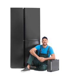 Male technician with tool box near refrigerator on white background