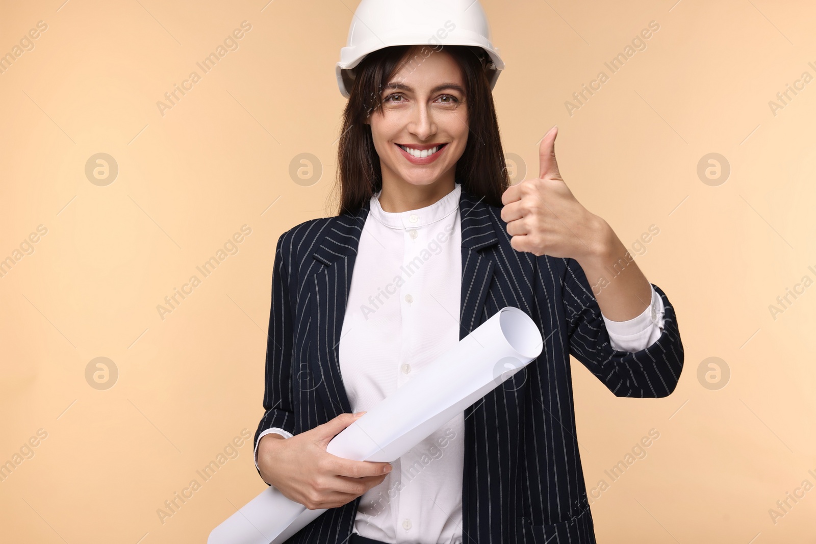 Photo of Architect in hard hat with draft showing thumbs up on beige background