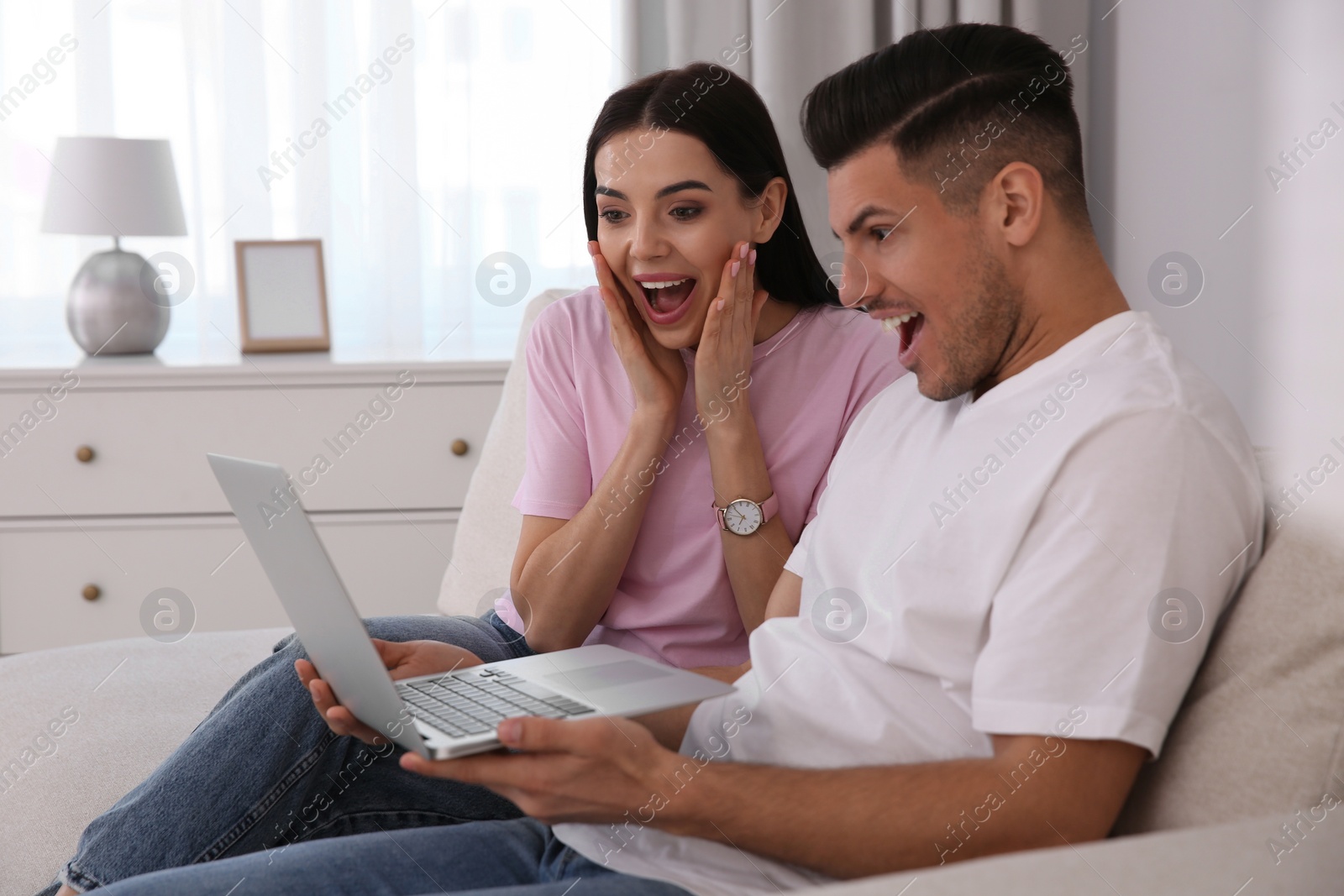 Photo of Emotional couple participating in online auction using laptop at home