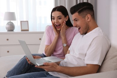 Photo of Emotional couple participating in online auction using laptop at home