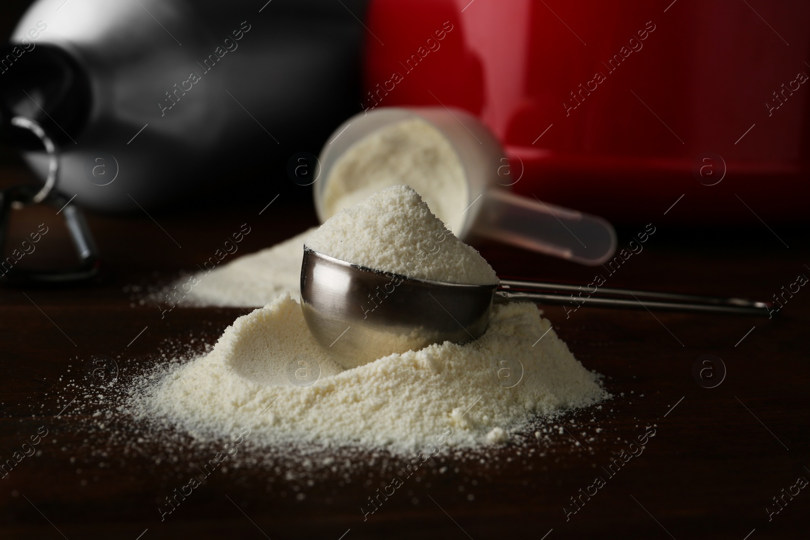 Photo of Measuring scoop of protein powder on wooden table, closeup