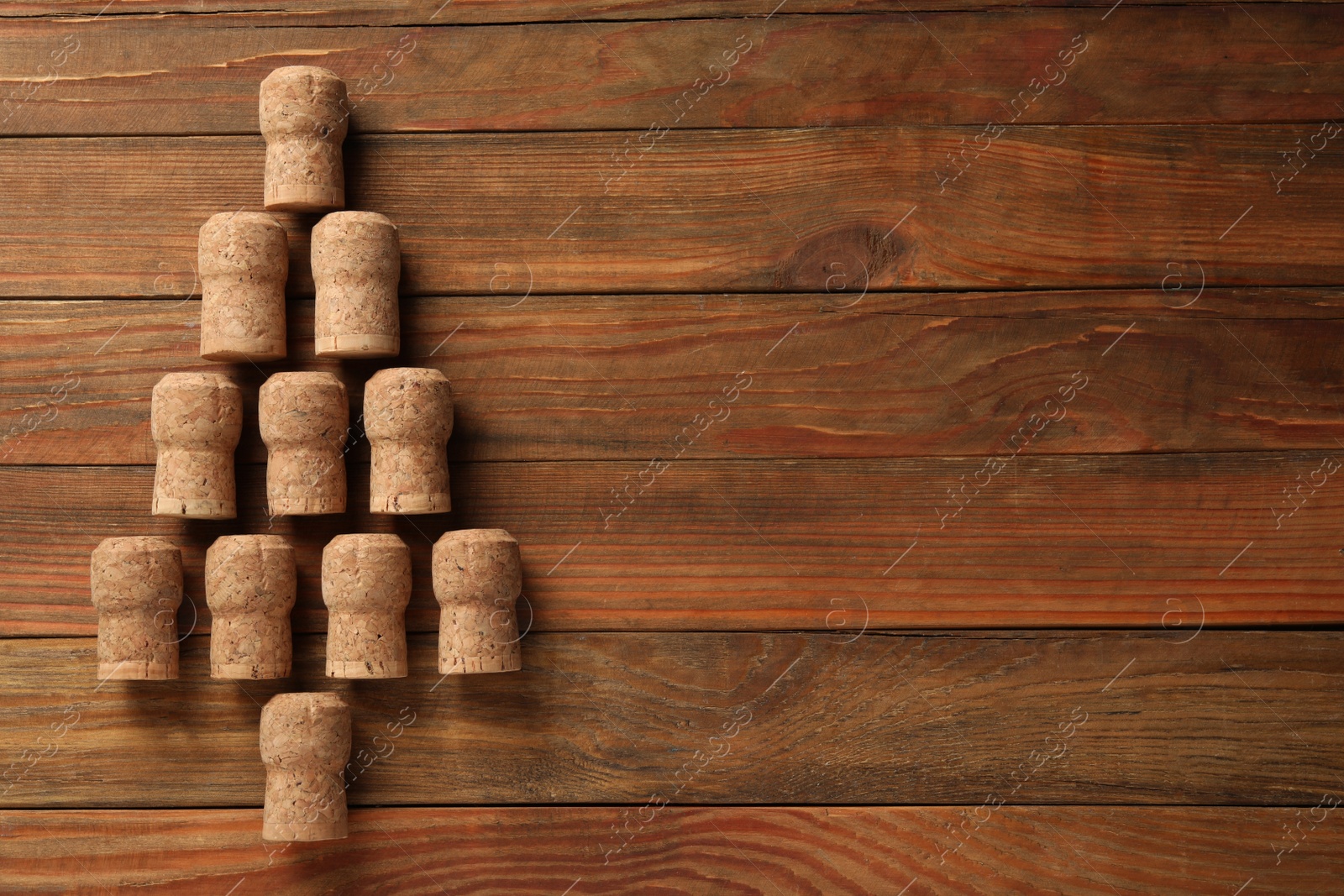 Photo of Christmas tree made of sparkling wine corks on wooden table, top view. Space for text