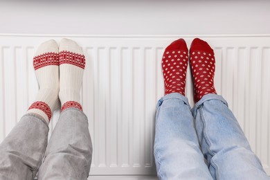 Photo of People warming feet near heating radiator, closeup