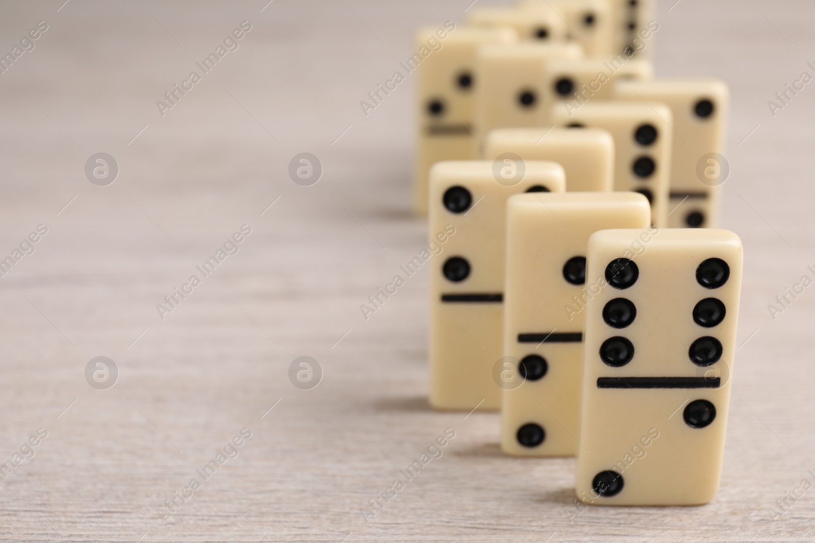 Photo of Domino tiles on wooden table, closeup. Space for text