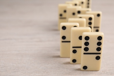 Domino tiles on wooden table, closeup. Space for text