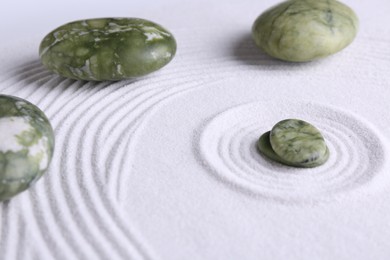 Photo of Zen concept. Stones and pattern on white sand, closeup