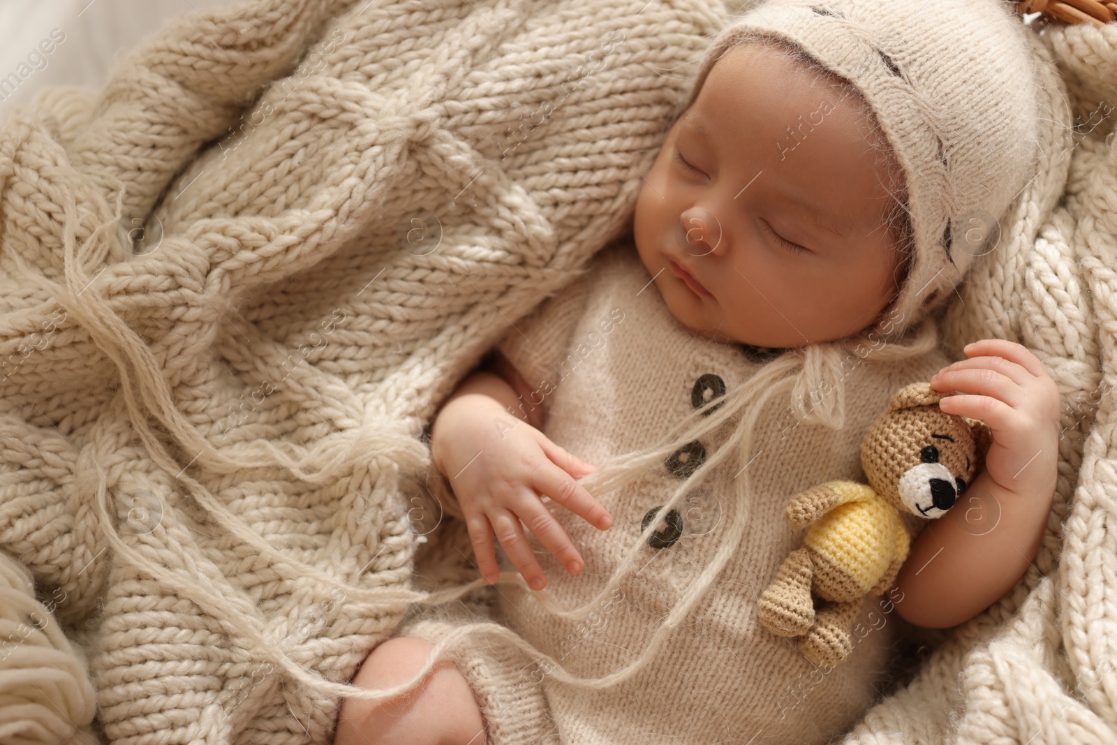 Photo of Adorable newborn baby with toy bear sleeping in basket, top view