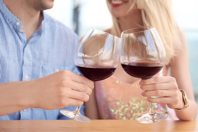 Young romantic couple with glasses of red wine at table