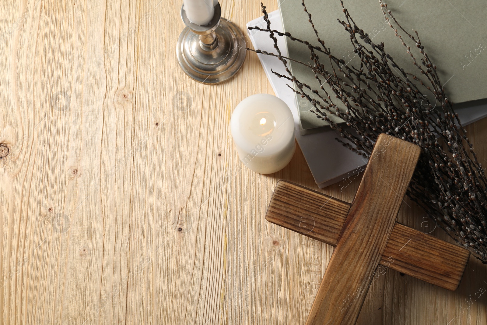 Photo of Cross, candles, books and willow branches on wooden table, flat lay. Space for text