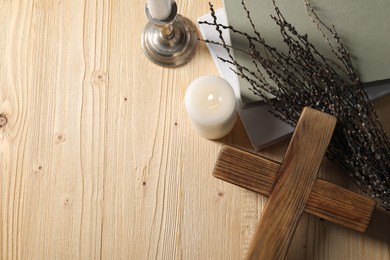 Cross, candles, books and willow branches on wooden table, flat lay. Space for text