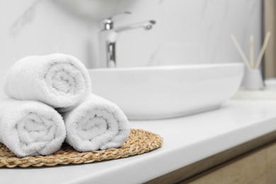 Photo of Rolled bath towels on white table in bathroom, space for text