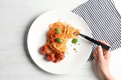 Photo of Woman having pasta with meatballs and tomato sauce at table, closeup