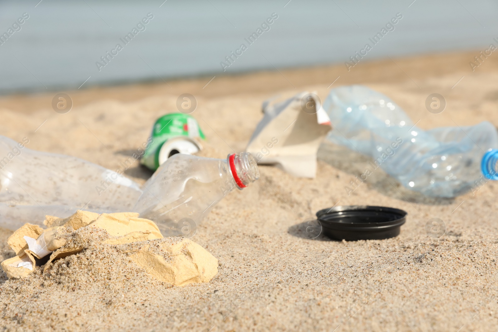 Photo of Garbage scattered on beach near sea, closeup. Recycling problem