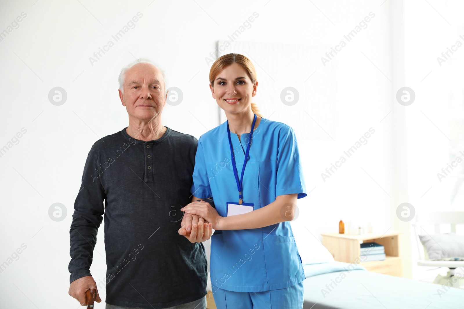 Photo of Nurse in uniform assisting elderly woman indoors