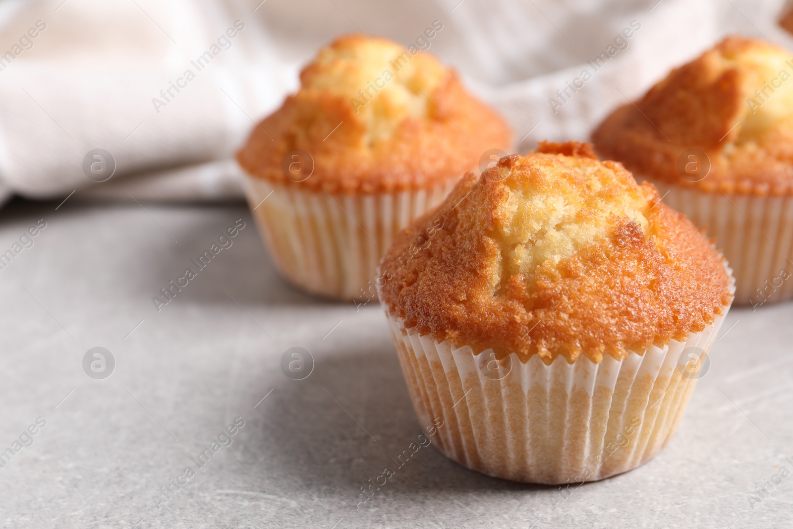 Photo of Tasty muffins on light grey table, closeup. Space for text