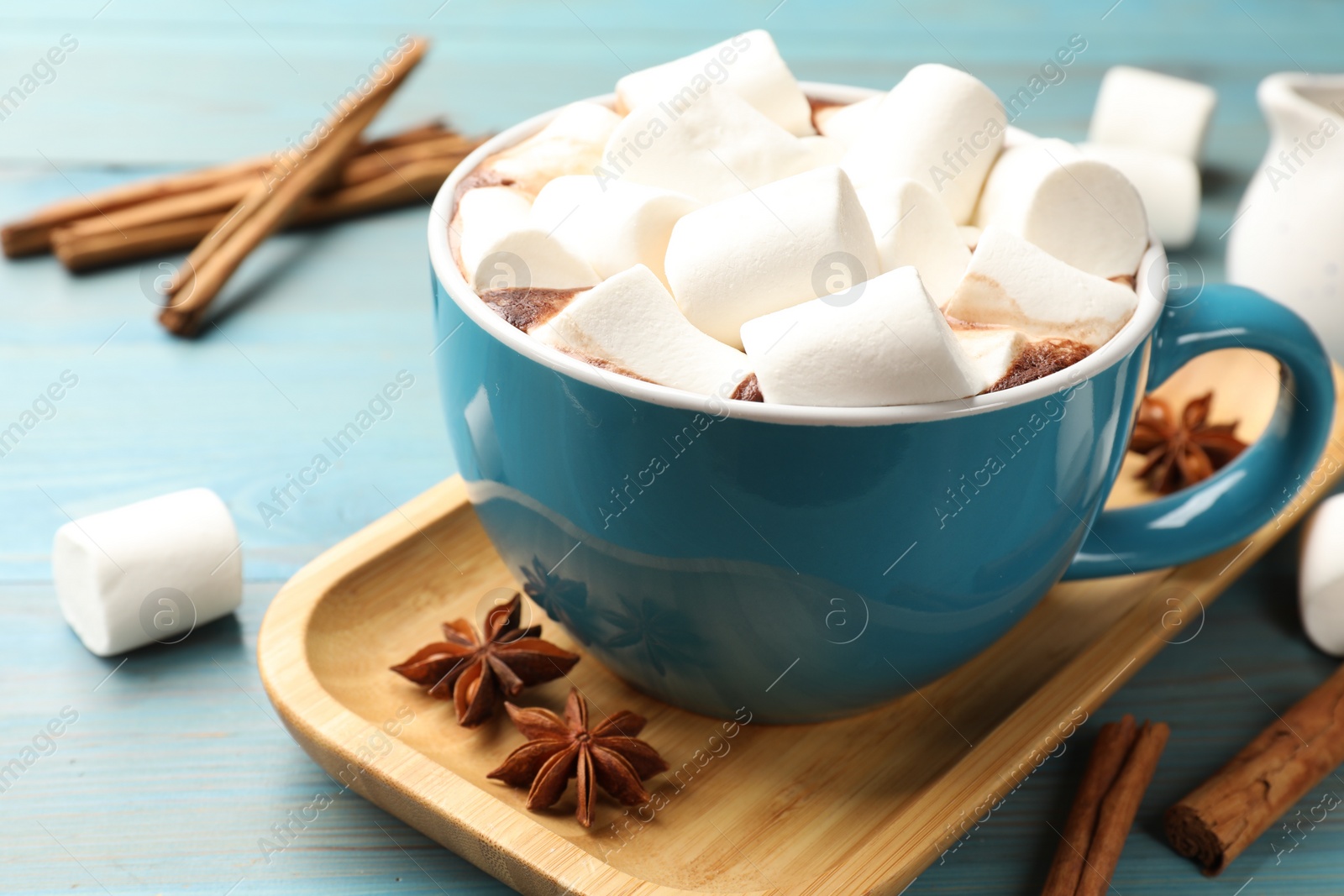 Photo of Tasty hot chocolate with marshmallows on light blue wooden table, closeup