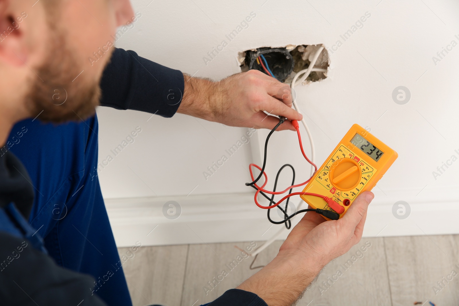 Photo of Electrician with tester checking voltage indoors, closeup