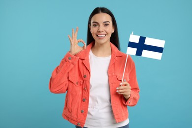 Image of Happy young woman with flag of Greece showing OK gesture on light blue background