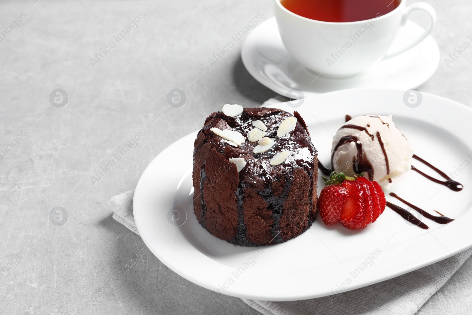 Photo of Plate of delicious fresh fondant with hot chocolate, ice cream and strawberry on table. Lava cake recipe