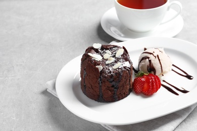 Plate of delicious fresh fondant with hot chocolate, ice cream and strawberry on table. Lava cake recipe