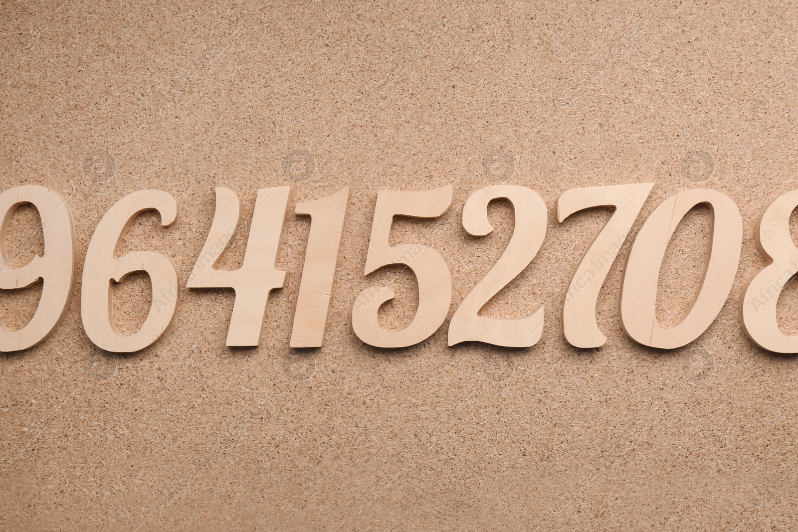 Photo of Many wooden numbers on fiberboard, flat lay