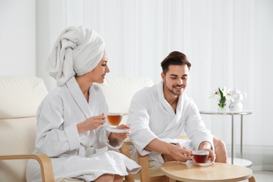 Photo of Romantic young couple with tea in spa salon