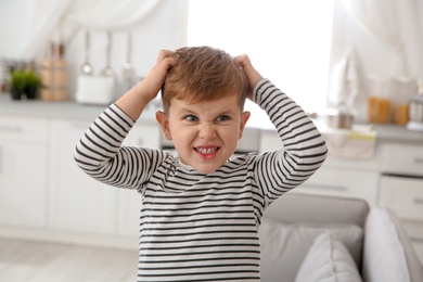 Photo of Little boy scratching head at home. Annoying itch