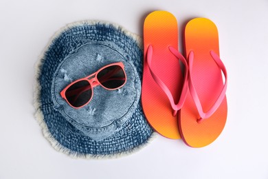 Sunglasses, hat and bright flip flops on white background, flat lay. Beach accessories
