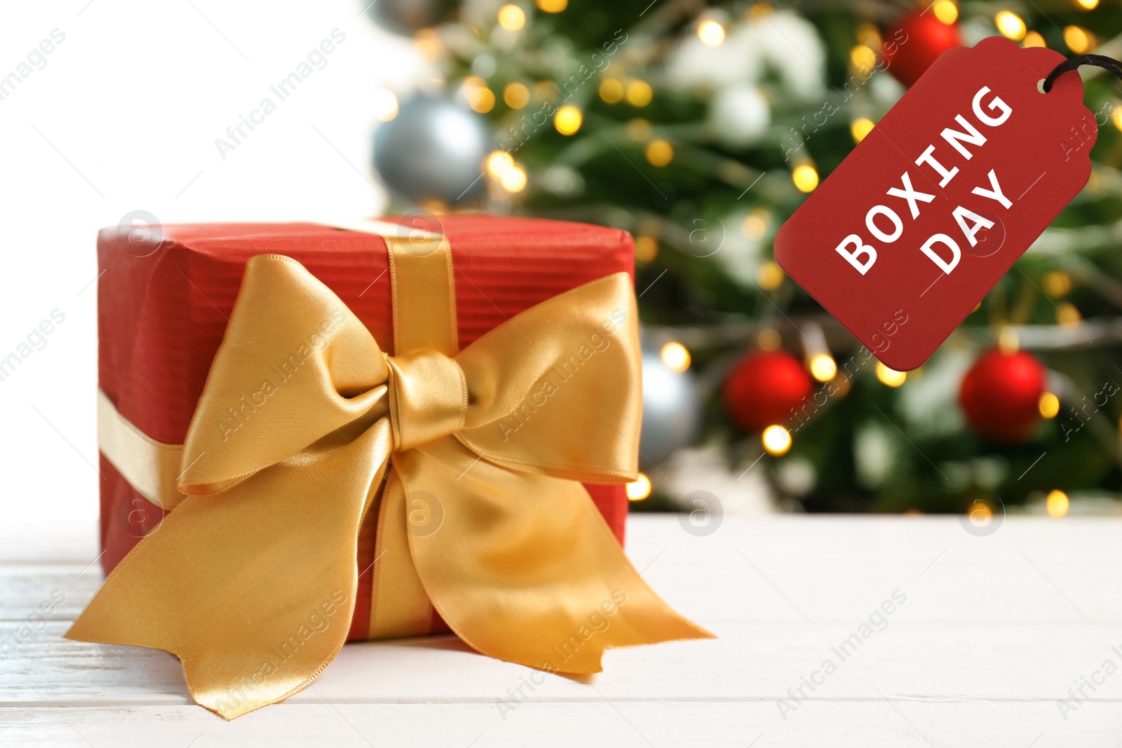 Image of Gift and tag with text Boxing Day against Christmas tree