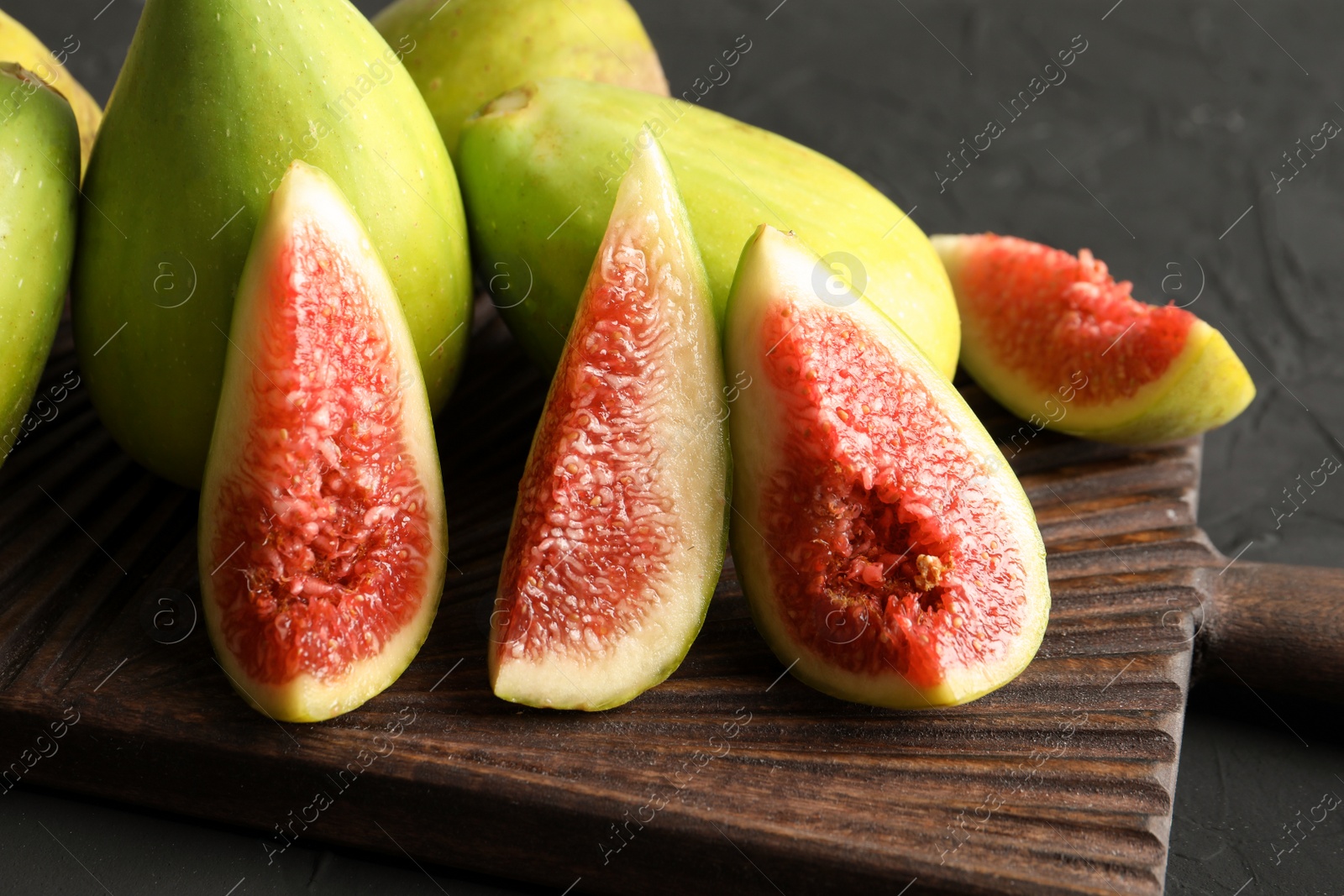 Photo of Cutting board with fresh ripe figs on dark background