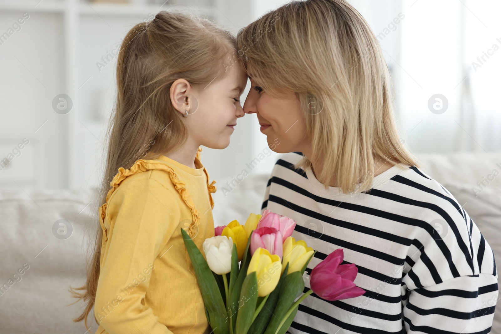 Photo of Little daughter congratulating her mom with bouquet of beautiful tulips at home. Happy Mother's Day