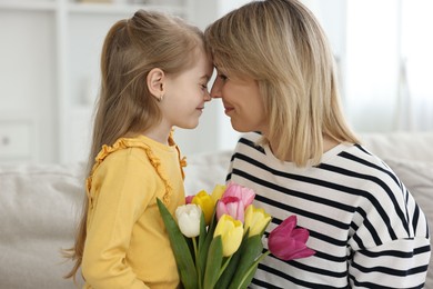 Little daughter congratulating her mom with bouquet of beautiful tulips at home. Happy Mother's Day