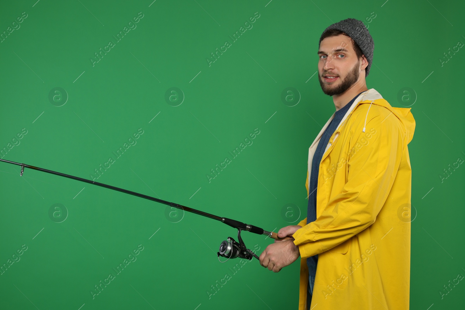 Photo of Fisherman with fishing rod on green background, space for text