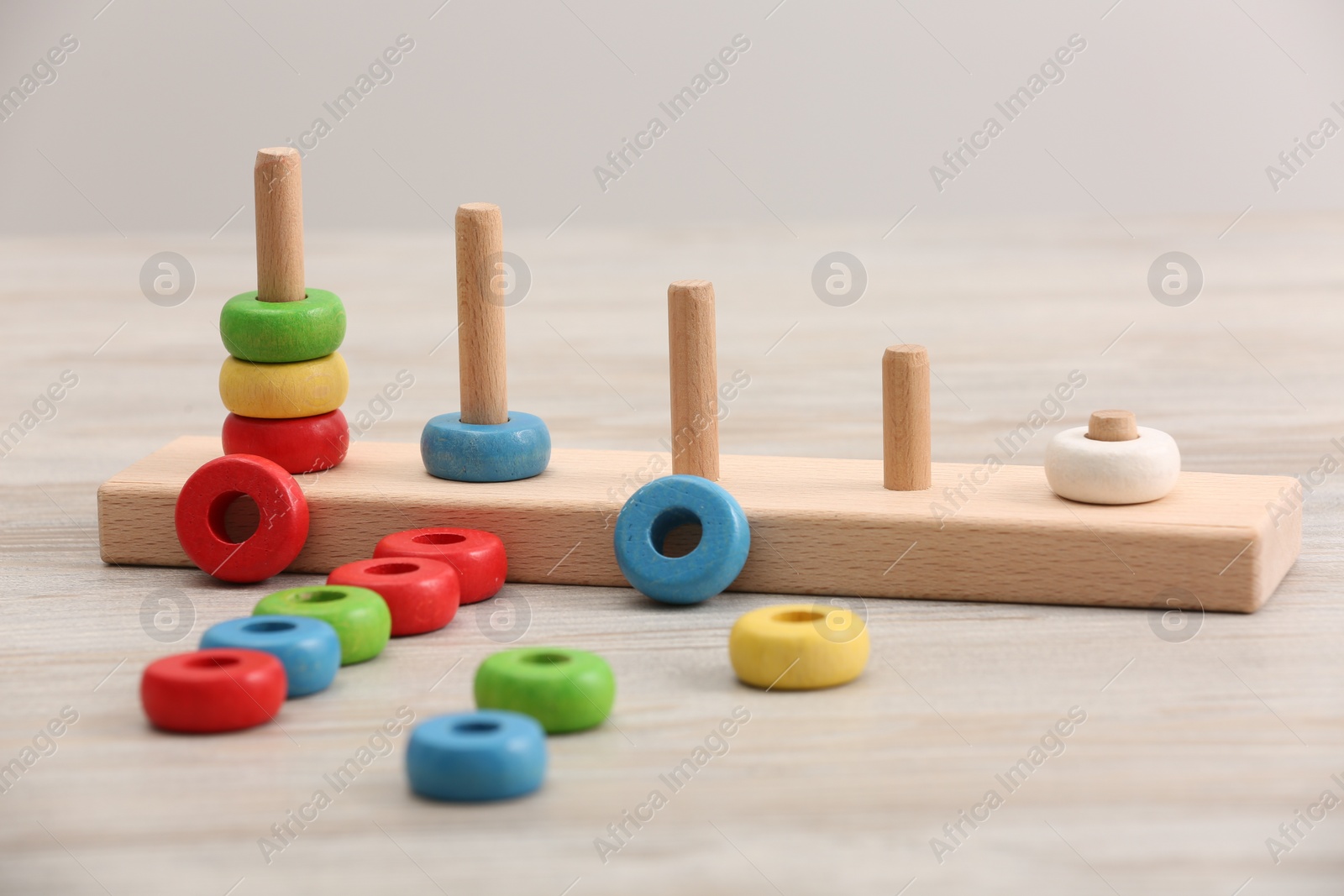 Photo of Educational toy for motor skills development. Stacking and counting game pieces on light wooden table