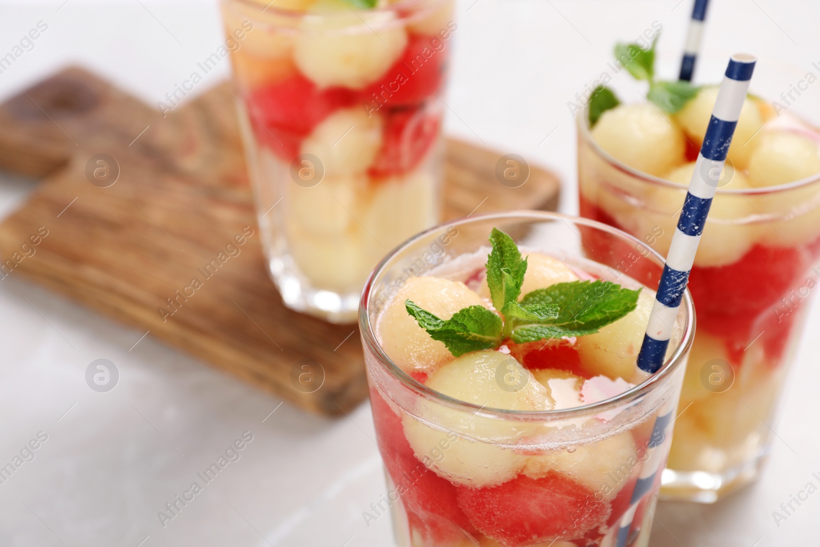 Photo of Glasses with tasty melon and watermelon ball drink on light table