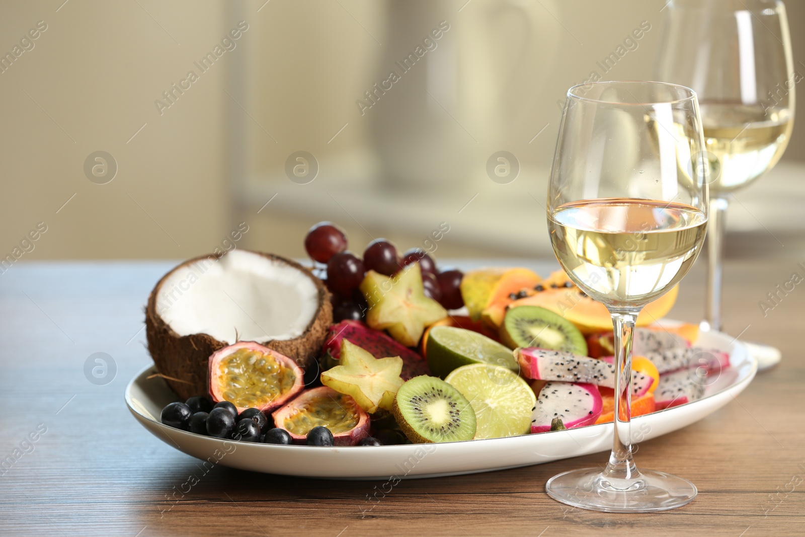 Photo of Delicious exotic fruits and wine on wooden table