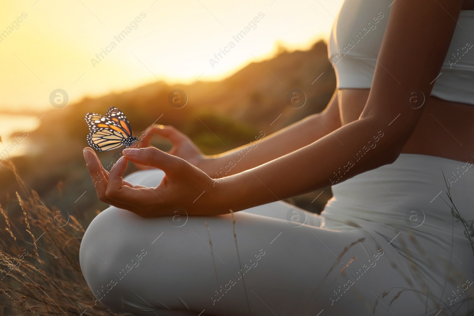 Image of Woman meditating outdoors at sunset, closeup view