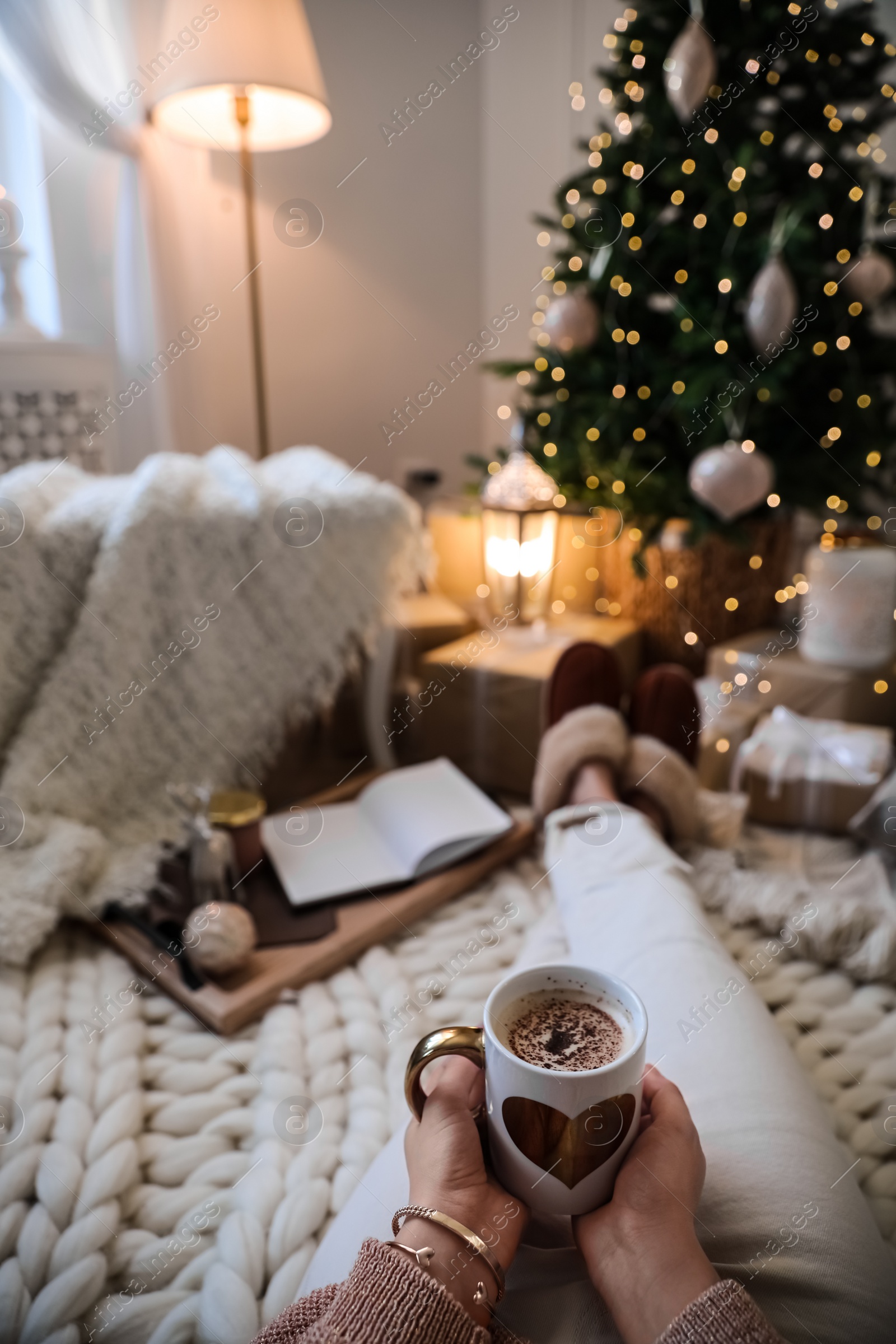 Photo of Woman with cup of cocoa in room decorated for Christmas, closeup