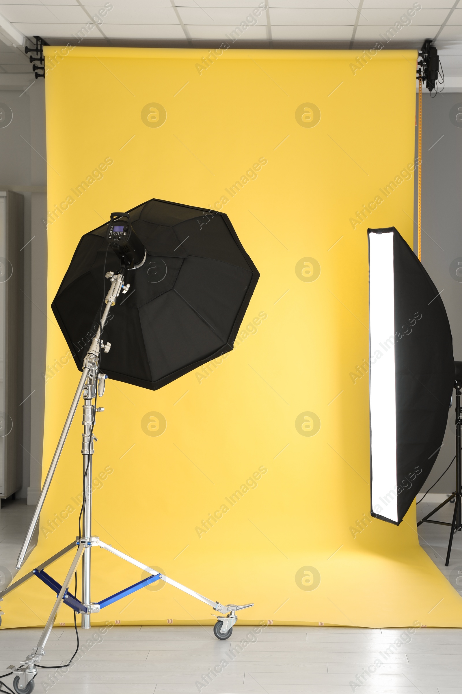 Photo of Yellow photo background and professional lighting equipment in modern studio