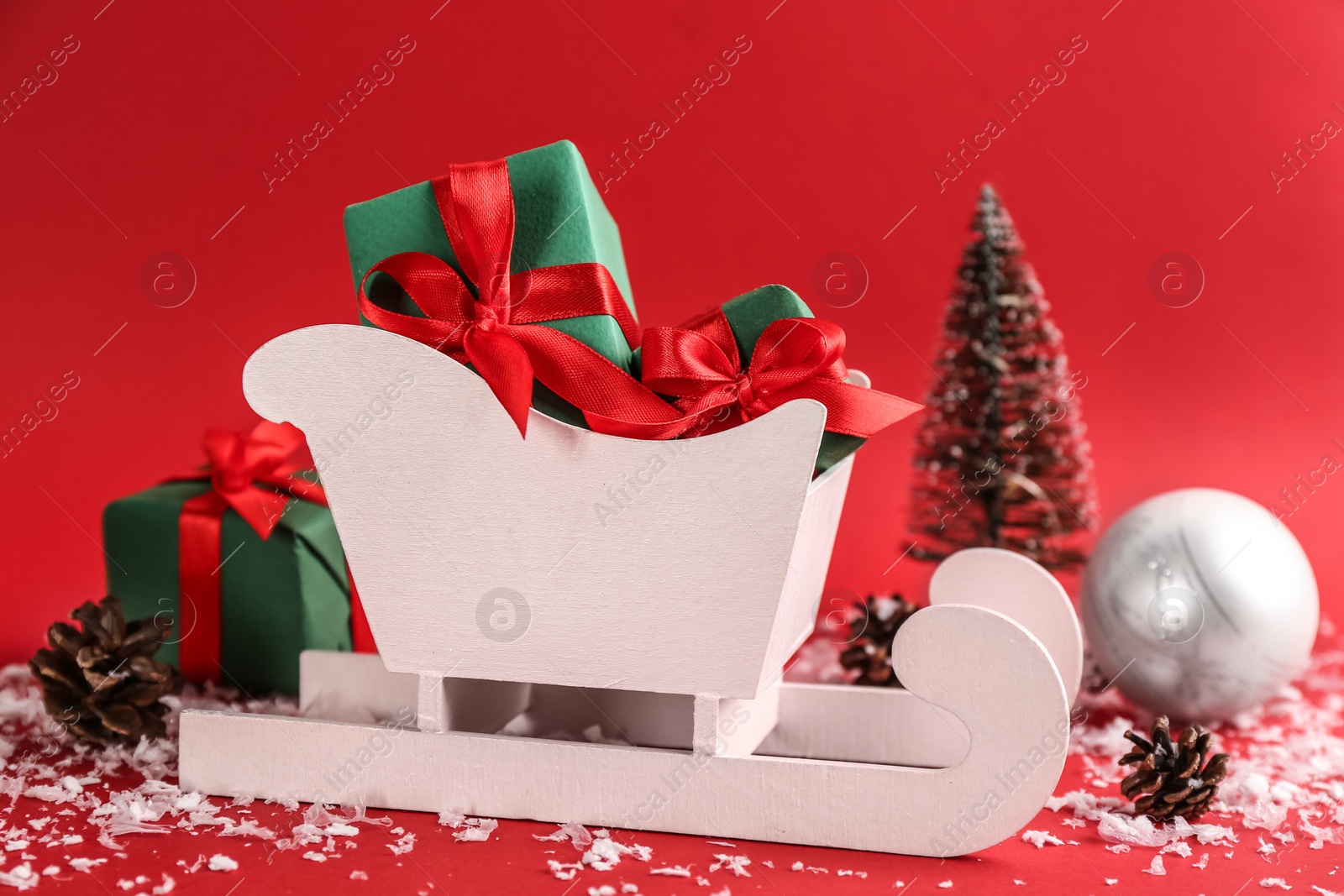 Photo of Beautiful Christmas composition with miniature sleigh on red background