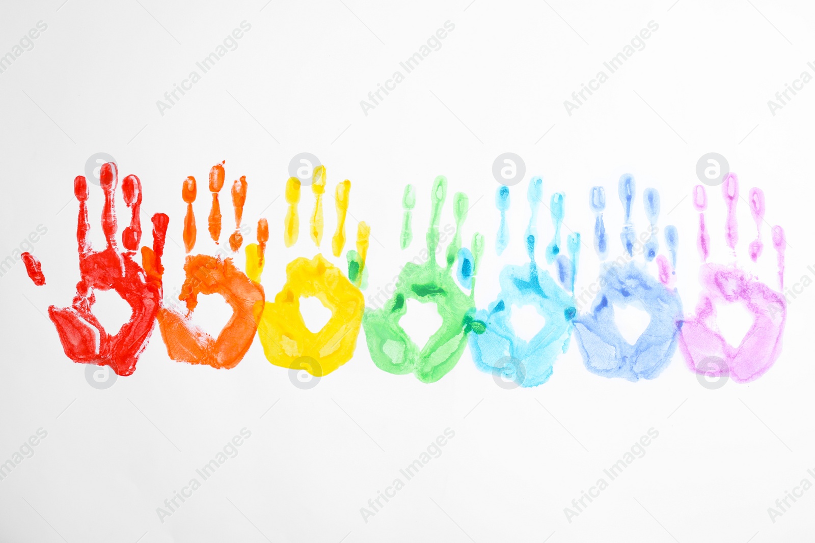 Photo of Handprints made with bright paints on white background, top view. Rainbow colors