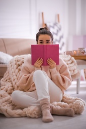 Beautiful young woman with book relaxing at home. Cozy atmosphere