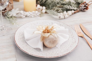 Photo of Festive place setting with beautiful dishware, cutlery and decor for Christmas dinner on white wooden table