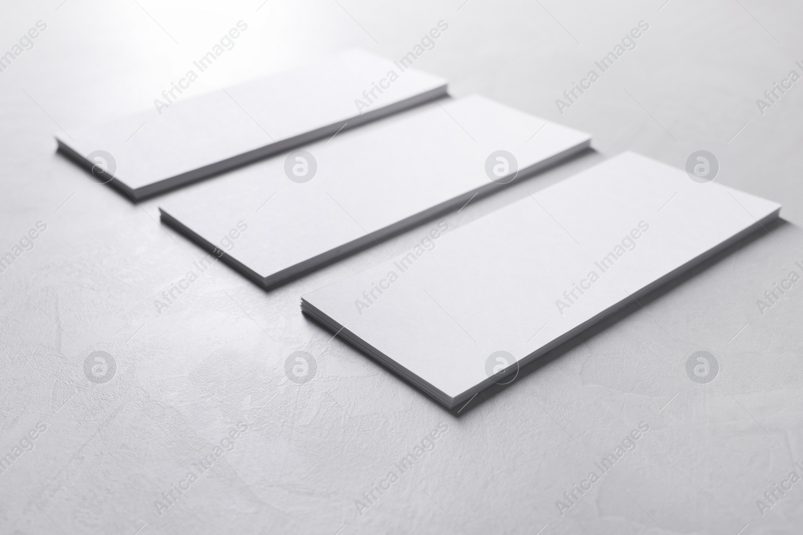 Photo of Blank business cards on light grey textured table, closeup. Mockup for design