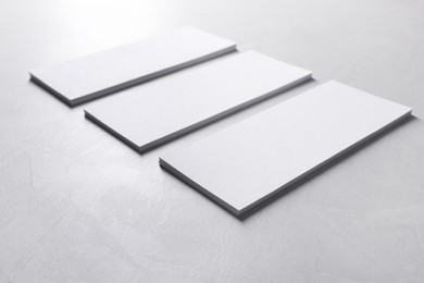 Blank business cards on light grey textured table, closeup. Mockup for design