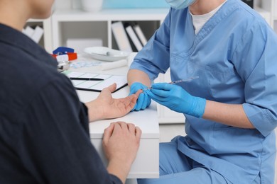 Photo of Laboratory testing. Doctor taking blood sample from patient at white table in hospital, closeup